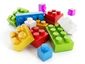 Colorful building block toy parts isolated on white background suggesting a modular (piece by piece) marketing approach