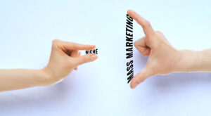 Photo illustration showing demonstrating the choice between narrow niche and wider mass marketing, with pinched fingers representing niche and widespread fingers representing mass marketing