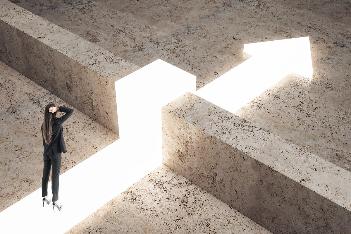 Thoughtful businesswoman with glowing arrow going over concrete fence. Represents the path to overcoming a challenge.